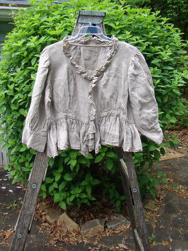 Magnolia Pearl Homespun Linen Snap Jacket Flaxen OSFA displayed on a wire hanger; features include ruffled neckline, snap line, lower cuffed sleeves, and signature Pearl Patch, hanging on a step-ladder outside.