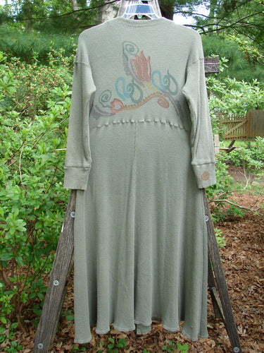 Long-sleeved 1995 Thermal Soliloquy Dress with abstract architectural paint, ribbed lower sleeves, and sweeping hemline, hung outdoors on a swing.