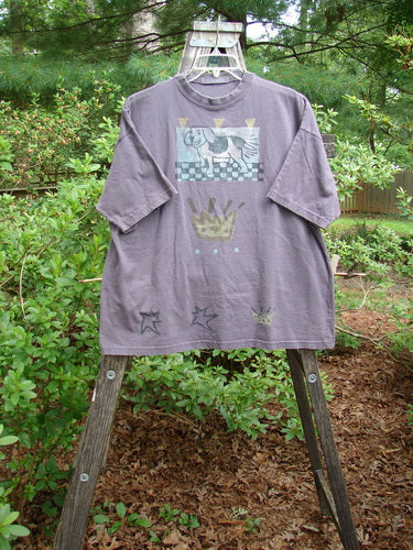 Alt text: 1995 Short Sleeved Tee Silly Pup Bloomsberry Altered Size 2 displayed on a wooden easel, featuring a dog with a crown and floral details, showcasing vintage Blue Fish Clothing's unique style.