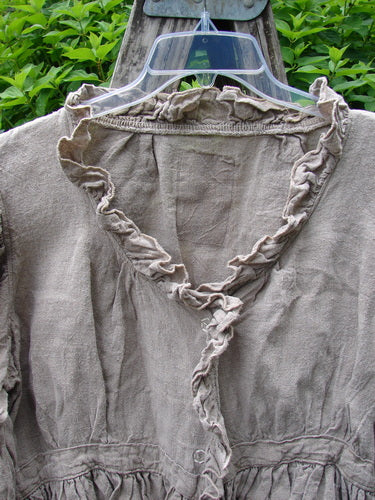 Magnolia Pearl Homespun Linen Snap Jacket Flaxen OSFA hangs outdoors, showcasing its ruffled V-neckline, gathered waist, long sleeves, and distinctive Pearl Patch, embodying vintage charm and creative individuality from Bluefishfinder.com.