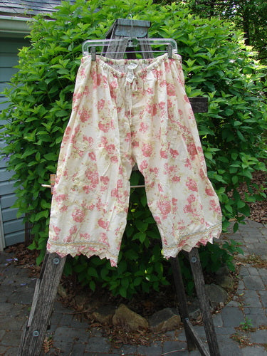 Magnolia Pearl Patched Khloe Bloomer Roses Are Red OSFA displayed on a hanger, featuring a cream with pink floral print, lace-trimmed hem, and drawstring waist, embodying vintage charm and creative expression.