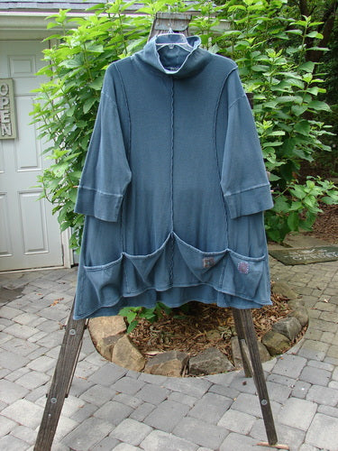 Barclay Patched Thermal Quad Drop Pocket Tunic Dress Blue Tealen Size 2 hanging on a rack, showcasing its double-layered turtleneck, four drop pockets, and whimsical nature-themed patches.