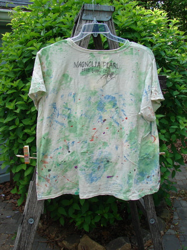 Magnolia Pearl Cotton Jersey Boyfriend Tee Songbird Floral OSFA hangs on a ladder, showcasing its soft cotton with a paint-splattered design and faint MAGNOLIA PEARL Love Song Co. text on the back.