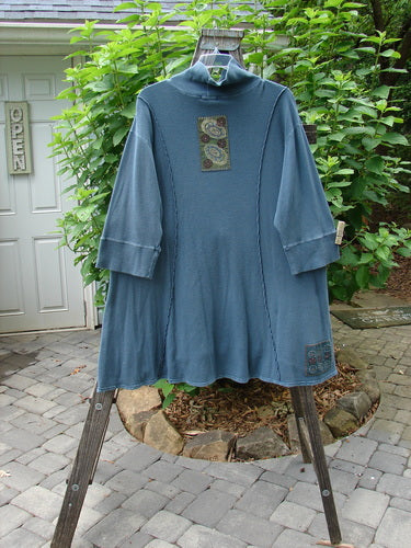 Barclay Patched Thermal Quad Drop Pocket Tunic Dress Blue Tealen Size 2 displayed on a rack with its unique double-layered turtleneck, widening hem, and whimsical nature-themed patches.