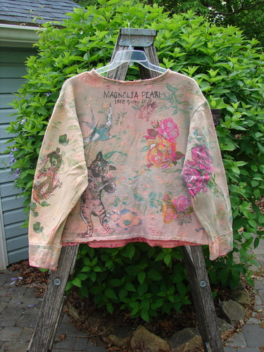 Magnolia Pearl Fleece Lucky Anna Glitter Sweatshirt Marais OSFA displayed on a ladder, featuring distressed edges, a hand-painted design with roses, birds, and cat motifs, embodying a vintage aesthetic.