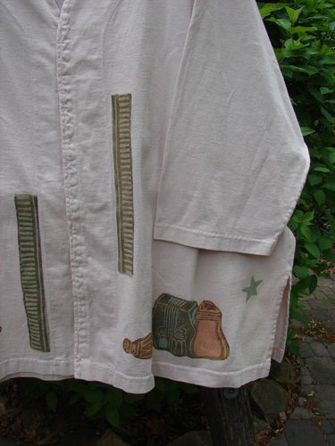1993 Resort PJ Top Diner Treat Tea Dye Size 2, a knee-length off-white garment with elbow-length sleeves, features unique motifs including vertical “zippers,” a star, and boots, hanging against greenery.