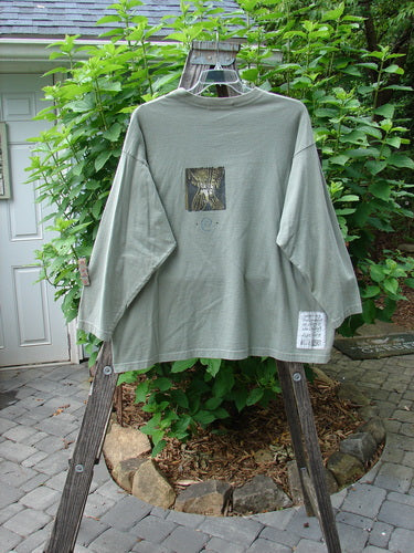 1996 Long Sleeved Tee Triple Fish Cricket Size 2 displayed on a hanger, showcasing drop shoulders, a thicker ribbed neckline, and signature Blue Fish patch with detailed vintage triple fish theme paint.