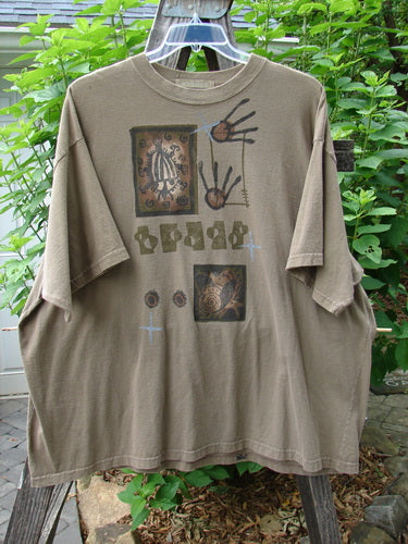 1995 Short Sleeved Tee Snail Garden Bramble Size 2, featuring a graphic snail garden design, ribbed neckline, drop shoulders, and a boxy shape, displayed outdoors with visible mended pinhole on the upper front shoulder.