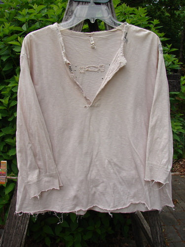 Magnolia Cotton Jersey Tobacco Picker's Henley Tee Tea Stain OSFA draped on a ladder, showcasing its distressed raw edges, tattered cuffs, and three-quarter sleeves with pearly buttons and contrasting stitch accents.