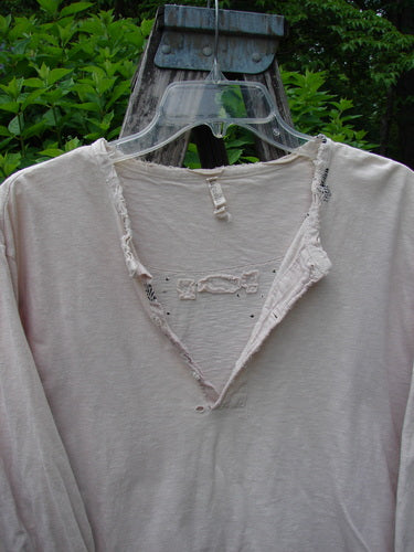 Magnolia Cotton Jersey Tobacco Picker's Henley Tee Tea Stain OSFA, displayed on a hanger, features frayed neckline, tattered edges, and small holes, showcasing its vintage charm and lightweight, super soft cotton jersey texture.