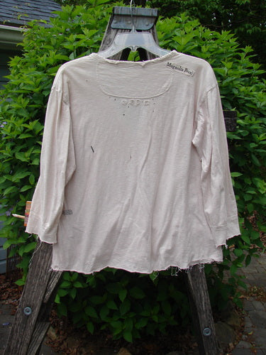 Magnolia Cotton Jersey Tobacco Picker's Henley Tee in Tea Stain draped over a stepladder, showcasing a frayed hem, paint flecks, and three-quarter cuffed sleeves in an outdoor garden setting.