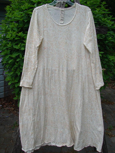 Magnolia Pearl Cotton Dylan Dress Softest Floral Naranja OSFA, featuring a scooped neckline, subtle floral print, and unique distressing details, hanging elegantly on a wooden hanger in a lush green setting.