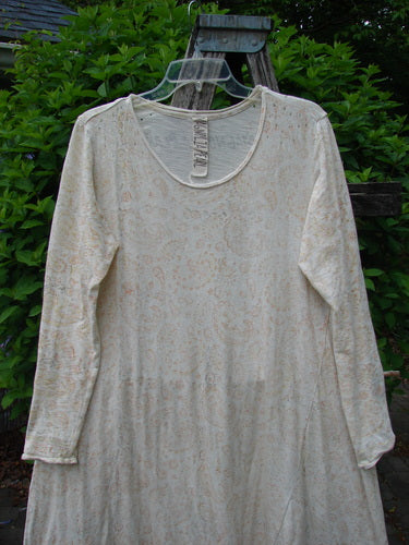 Magnolia Pearl Cotton Dylan Dress Softest Floral Naranja OSFA displayed on a wooden trellis. Features include a rolled neckline, tighter lower sleeves, A-line flair, raw seams, and upper distressing.