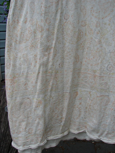 Magnolia Pearl Cotton Dylan Dress Softest Floral Naranja OSFA, draped outdoors, showcases its subtle floral print and distinctive features like a rounded neckline, tighter sleeves, and distressed seams, reflecting Bluefishfinder.com's vintage charm.