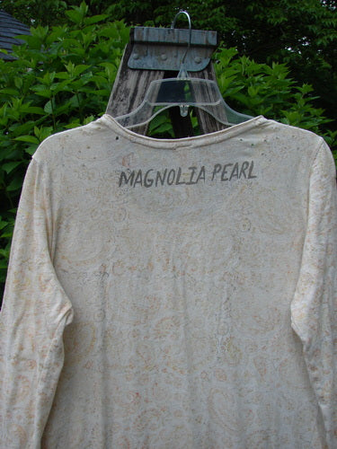 Magnolia Pearl Cotton Dylan Dress Softest Floral Naranja OSFA features a light-cream paisley print with a relaxed A-line cut, rolled neckline, and distressed seams. Displayed on a hanger against a natural backdrop.