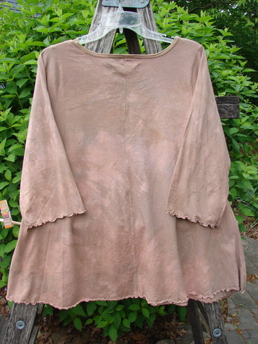 Barclay Three Quarter Sleeved Cafe Tee in muted brown, featuring a rounded neckline and wavy edges, hangs on a wooden ladder, set against greenery, embodying BlueFishFinder's vintage, creative ethos.