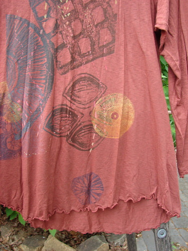 Barclay Modal Long Sleeved A Lined Tee Fall Woods Cassia Size 0: A dusty-rose tunic with ruffled hem, featuring abstract sunburst and grid motifs in muted tones, hanging to dry.