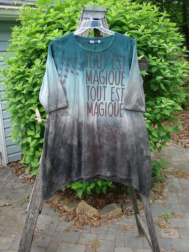 Barclay Wander Tunic Tee Magic Mottled Vintage Teal Size 0, featuring a loose-fitting, tie-dyed design with TOUT EST MAGIQUE and bird silhouettes, draped outdoors over a frame.