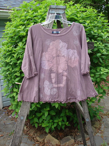 Barclay Crop A Lined Cafe Tee draped on ladder, featuring a loose-fit, scalloped hem, and oversized floral print in a muted mauve shade, reflecting a bohemian style.