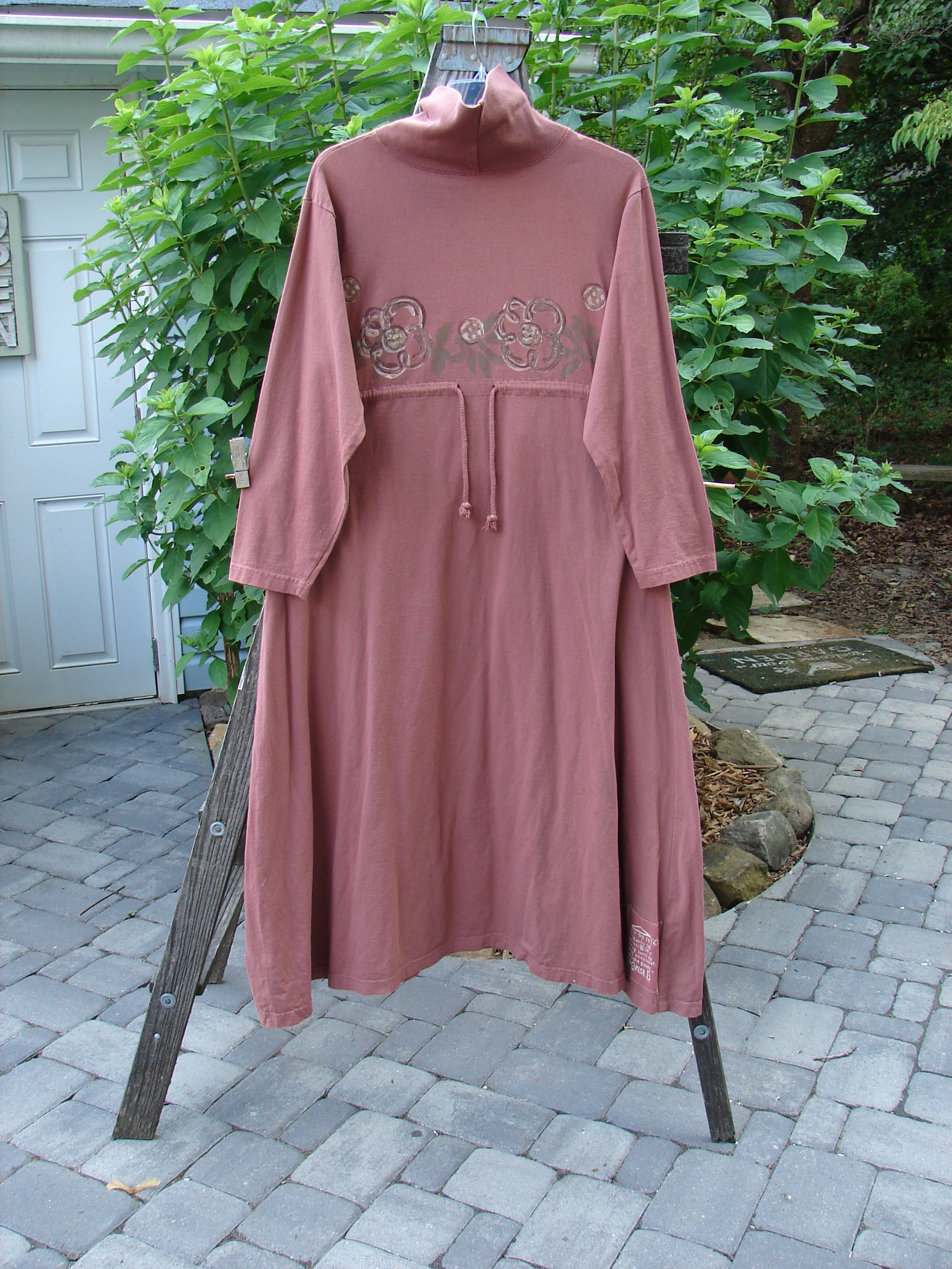 1995 Omega Dress Celestial Garden Altered Clove Size 1 on a stand, showcasing a heavy ribbed turtleneck, drop shoulders, A-line flare, and drawcord backline in organic cotton fabric.