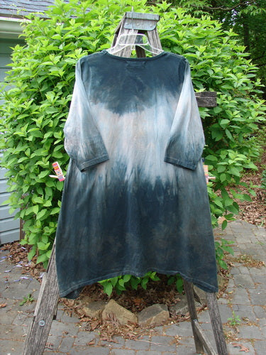 Barclay Wander Tunic Tee Rain Star Mottled Night Size 0 displayed outdoors, featuring a gradient tie-dye pattern and three-quarter sleeves, elegantly draped over a wooden ladder amidst lush greenery.