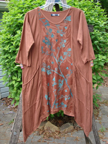 Barclay Wildflower Tunic Floral Sprig Harvest Size 0: A loose-fitting tunic with asymmetrical hem, three-quarter sleeves, and floral sprig print, featuring seam pockets and raw-edged front panel, hanging outdoors.