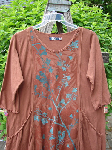 Barclay Wildflower Tunic Floral Sprig Harvest Size 0 features a loose fit with a stylized floral print, three-quarter sleeves, raw-edged front panel, and exterior pockets, hanging outdoors.