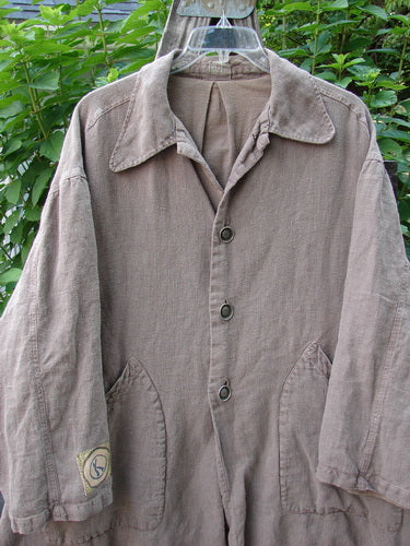 1999 PMU Single Patch Hemp Yard Coat Shale Size 2 displayed on a hanger, featuring metal buttons, adjustable side tabs, and front drop pockets, showcasing the coat's texture and drape.