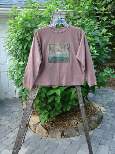 A 1994 PMU Patched Long Sleeved Tee Rosewood Size 1 displayed on a wooden rack, showcasing its rolled neckline, shortened hemline, and unique playground and cloud-themed patches.