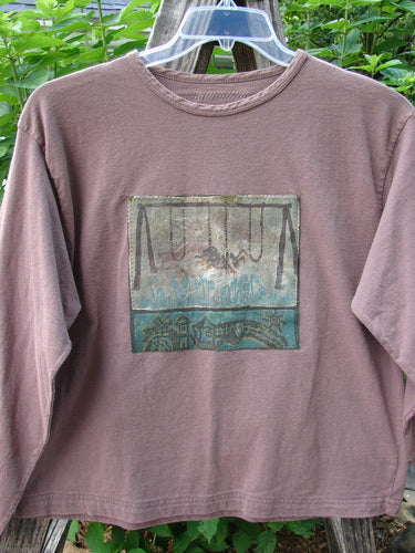 Alt text: 1994 PMU Patched Long Sleeved Tee Rosewood Size 1, featuring a rolled neckline, shortened hemline, long sleeves, and unique playground and cloud-themed patches.