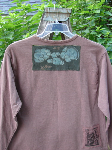 1994 PMU Patched Long Sleeved Tee Rosewood Size 1 displayed on a hanger, featuring a rolled neckline, cozy long sleeves, and playful playground and cloud-themed patches.