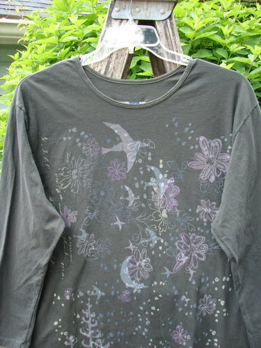 Barclay Long Sleeved Studio Tee Moon Gull Garden Ash Black Size 0, featuring pastel floral and bird motifs, hangs on a ladder. This whimsical design embodies Bluefishfinder.com's vintage-inspired creativity and individuality.