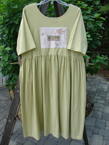 Green Barclay PMU Patched Flower Garden Dress in citron on a clothes rack, showcasing a scooped neckline, drop straight waist seam, front pocket, and fish school patches.