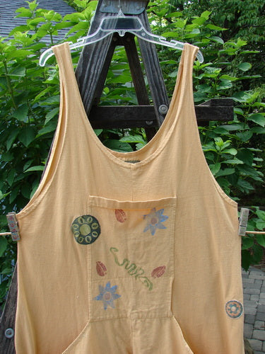 Alt text: 1991 PMU Farmer Brown Overall Pant Jumper Rear Rooster Goldenrod OSFA hanging on a clothesline, showcasing its unique painted pockets and patches.