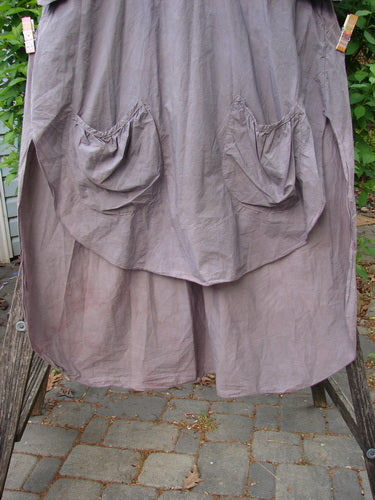 Barclay Percale Key Pocket Hi Low Dress with gathered patch pockets, clipped outdoors. This taupe-gray, knee-length dress features a unique rounded front-back length and handcrafted floral burst theme in lightweight cotton.
