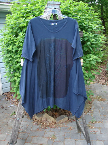Barclay Origami Tunic Top Night Garden Blue Ink Size 0 displayed draped over a wooden ladder, showcasing its asymmetrical hem, open sides, and raw flutter edgings, set on a stone patio.