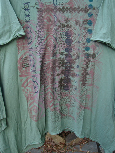 Barclay Origami Tunic Top Garden Block Spanish Moss Size 0, displayed outdoors, features a geometric graphic design on organic cotton, highlighting its unique tunic shape with open sides and raw flutter edges.