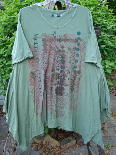 Barclay Origami Tunic Top Garden Block Spanish Moss Size 0: Loose-cut, olive-green tunic with abstract print, wide scooped neckline, batwing sleeves, and uneven drapey hem, hanging outdoors.