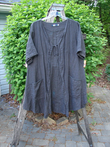 Barclay Linen Tie Pocket Cardigan Field Fern Black Size 0: A knee-length, loose-fitting tunic with a tie-front neckline and short sleeves, featuring large patch pockets, displayed on a wooden ladder.
