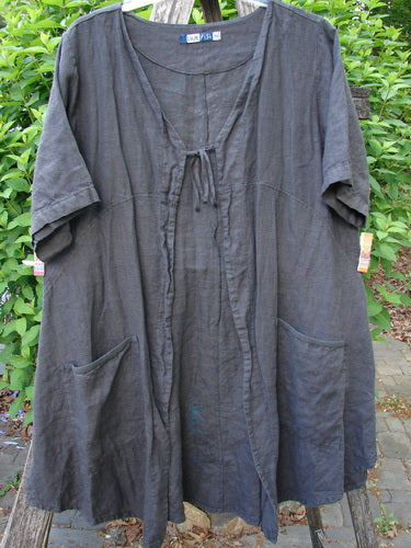 Barclay Linen Tie Pocket Cardigan Field Fern Black Size 0, displayed on a wooden ladder with green foliage, features wide short sleeves, V-neck tie, dual front pockets, and fern-themed paint accents.