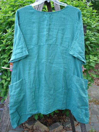 Barclay Linen Side Pocket Urchin Dress Chair Note Jade Size 0, featuring a forest-green, oversized, elbow-length tunic with a scooped neckline, front patch pockets, and a gently curved seam detail.