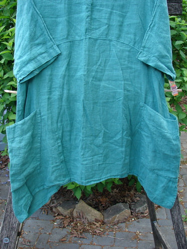 Barclay Linen Side Pocket Urchin Dress Chair Note Jade Size 0, features elbow-length sleeves, large front pockets, and varying hemline, displayed outdoors against greenery, reflecting Bluefishfinder's vintage-inspired creative ethos.