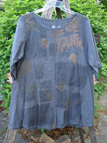 Barclay Linen Lucida Top Metallic Fern Blue Storm Size 0, featuring a loose fit with a fern-leaf print, displayed on a hanger over a wooden trellis, tags attached.