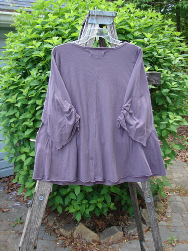 Barclay Draw Gather Sleeve Cafe Top Power Plum Size 0 displayed on a wooden stepladder with ruched bell sleeves and tunic-style cut, highlighting its flowing design and durable organic cotton fabric.