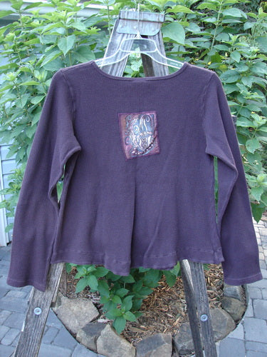 Barclay Patched Thermal Tuck Top Raisin Size 1 displayed on a hanger, featuring a rounded neckline, tear-shaped pocket, longer sleeves, and a distinctive steaming teacup patch on the back.