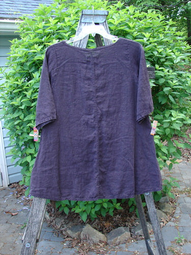 Barclay Linen A Line Top London 1844 Deep Burgundy Size 0, displayed on a wooden ladder stand, features a rounded neckline, elbow-length sleeves, and a slight A-line silhouette against a natural backdrop.
