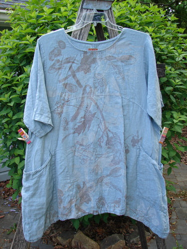 Barclay Linen Urchin Dress Leaf Floral Dusky Watercolor Size 1 displayed on a wooden ladder, featuring a loose fit, elbow-length sleeves, drop shoulders, curved empire waist, and double front pockets with a floral print.