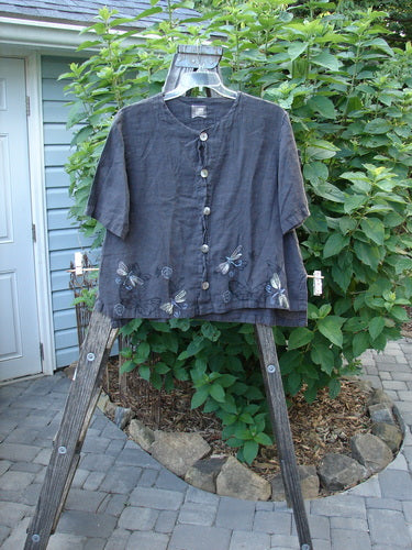 1999 Handkerchief Camp Shirt Dragonfly Raven Altered Size 1 displayed on a wooden hanger, showcasing its A-line shape, dragonfly-themed paint, and original shell buttons with a breezy, lightweight linen fabric.