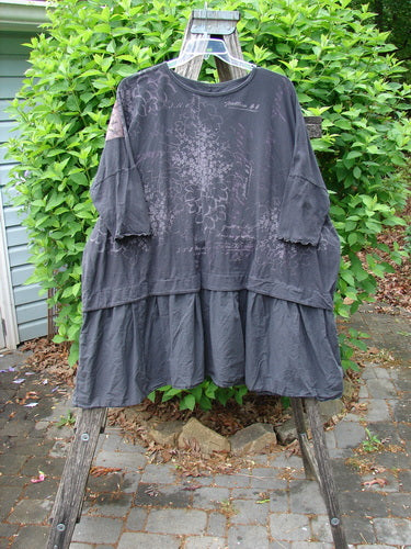 Barclay Patched Batiste Banded Flounce Esperanza Tunic Floral Storm OSFA features a loose, tiered design with elbow-length dolman sleeves and script-style print, hanging on an old wooden stepladder.
