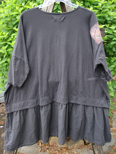 Barclay Patched Batiste Banded Flounce Esperanza Tunic Floral Storm OSFA displayed on a stepladder, highlighting its dropped waist, flouncy lower skirt, elbow-length dolman sleeves, and rear birdie patch.
